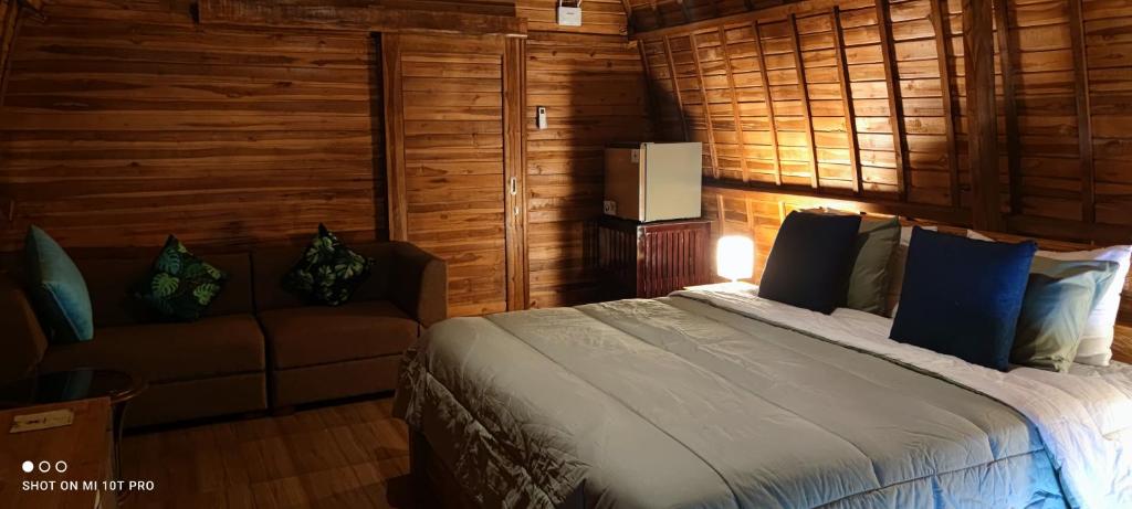 a bedroom with a bed and a couch at Sugita Wooden House 2 in Payangan