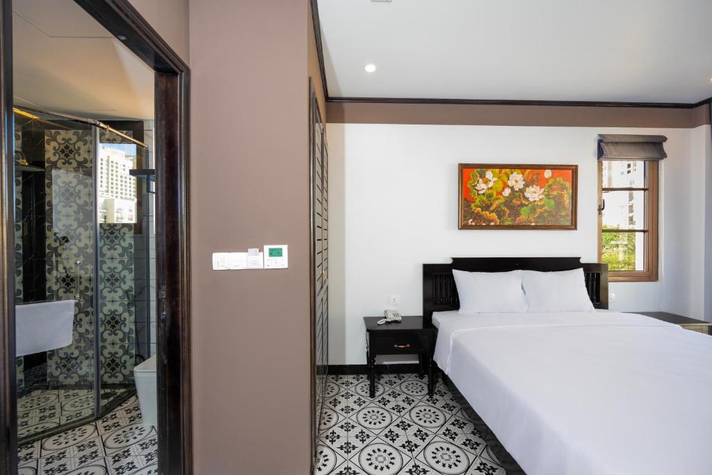 a bedroom with a white bed and a glass door at Thala Hotel Sorrento in Phu Quoc