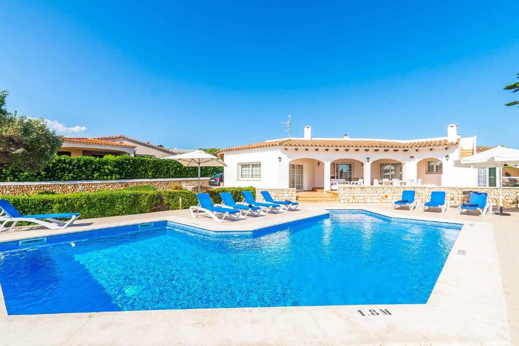 una villa con piscina frente a una casa en Arena Blanca, en Sant Lluis