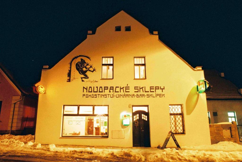 a building with a sign on it in the snow at Penzion Novopacké Sklepy in Nová Paka