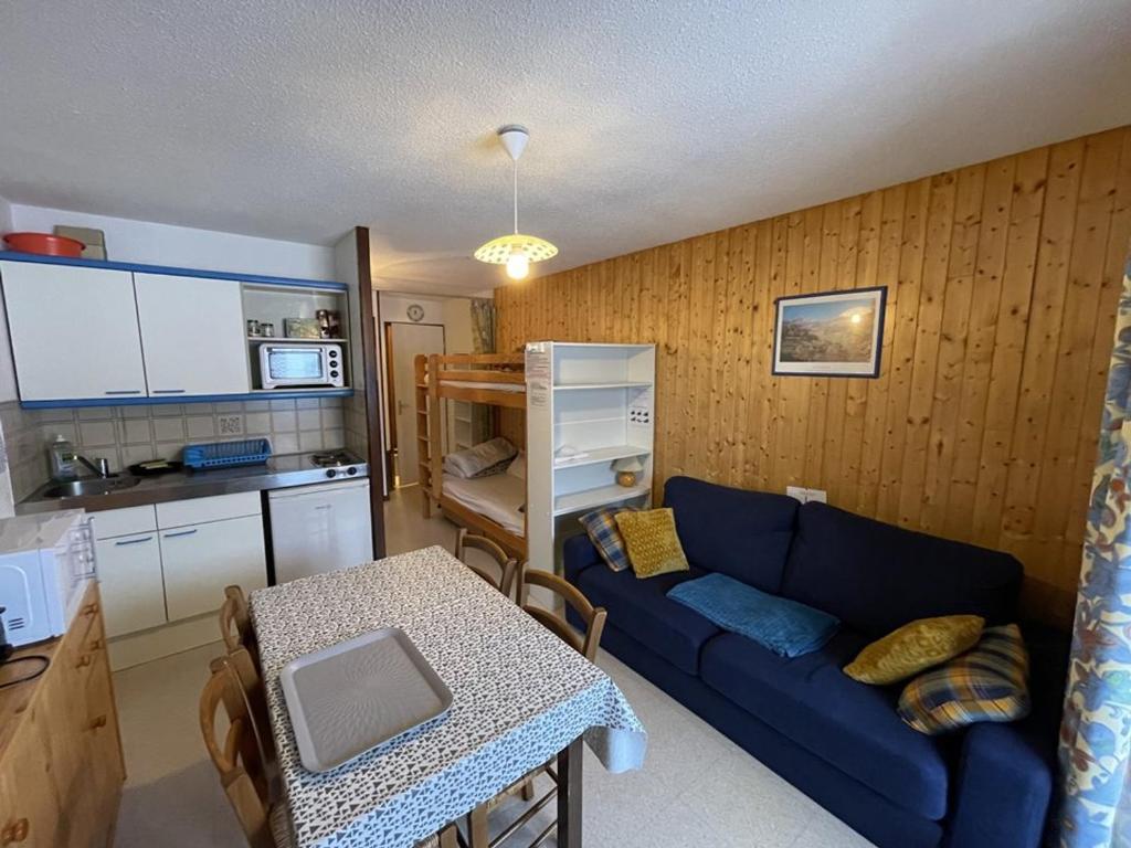 un salon avec un canapé bleu et une cuisine dans l'établissement Confortable T2 avec balcon au cœur de la station, proche pistes et commerces - FR-1-787-80, à Laveissière
