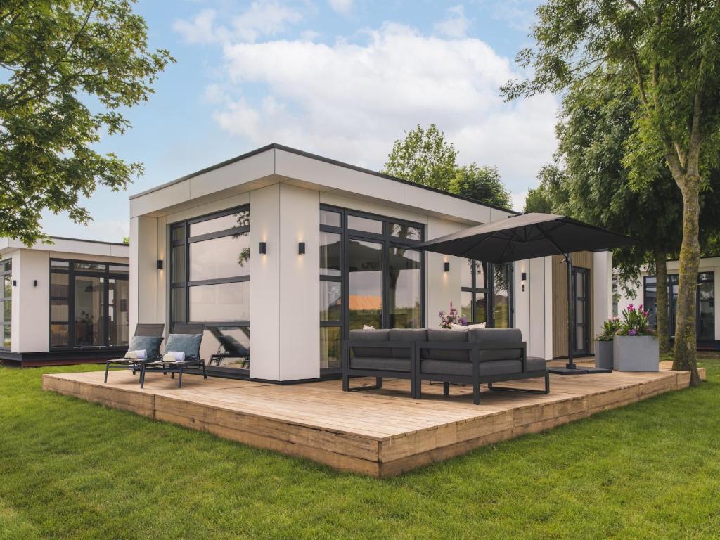 a pavilion with benches and an umbrella in a yard at Cozy Riverside Escape in Maurik