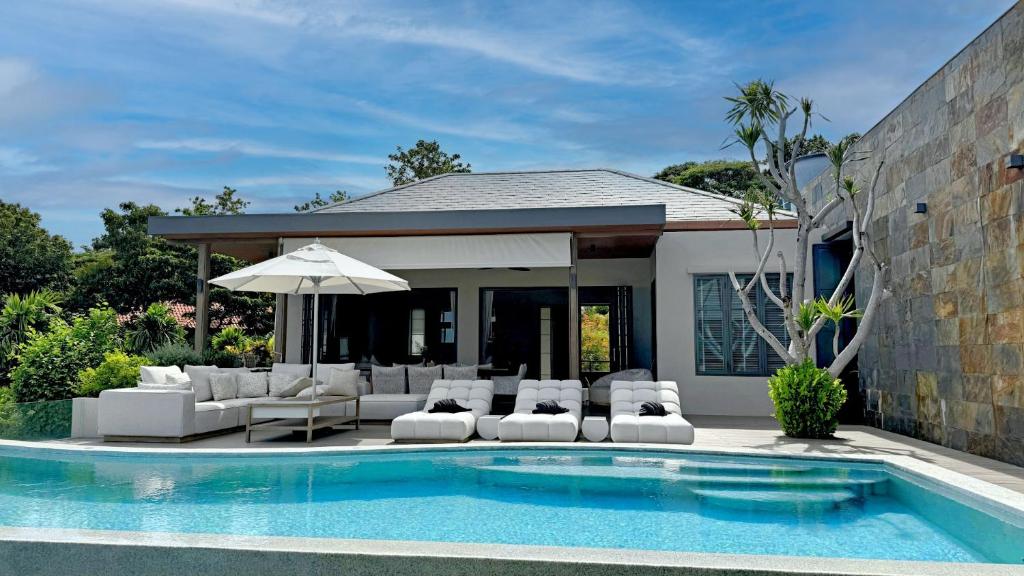 a pool with chairs and an umbrella next to a house at Villa Divano - by Sublime Samui Villas in Choeng Mon Beach