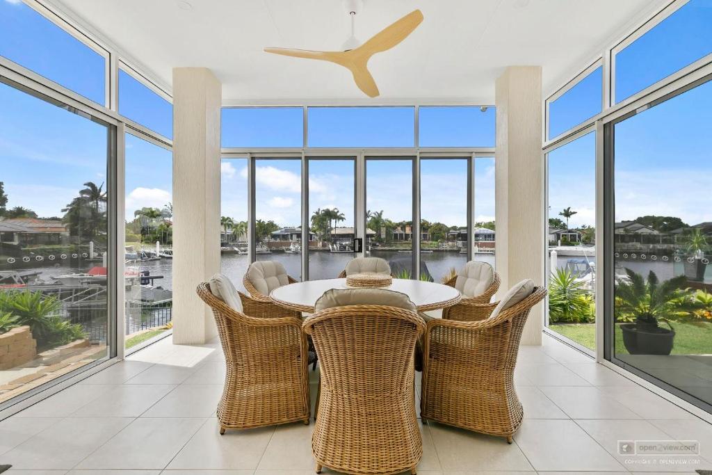 a dining room with a table and chairs and windows at HALYCON HOUSE in Banksia Beach