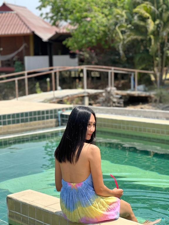 a woman in a dress sitting next to a swimming pool at JJ&amp;J Garden in Pai