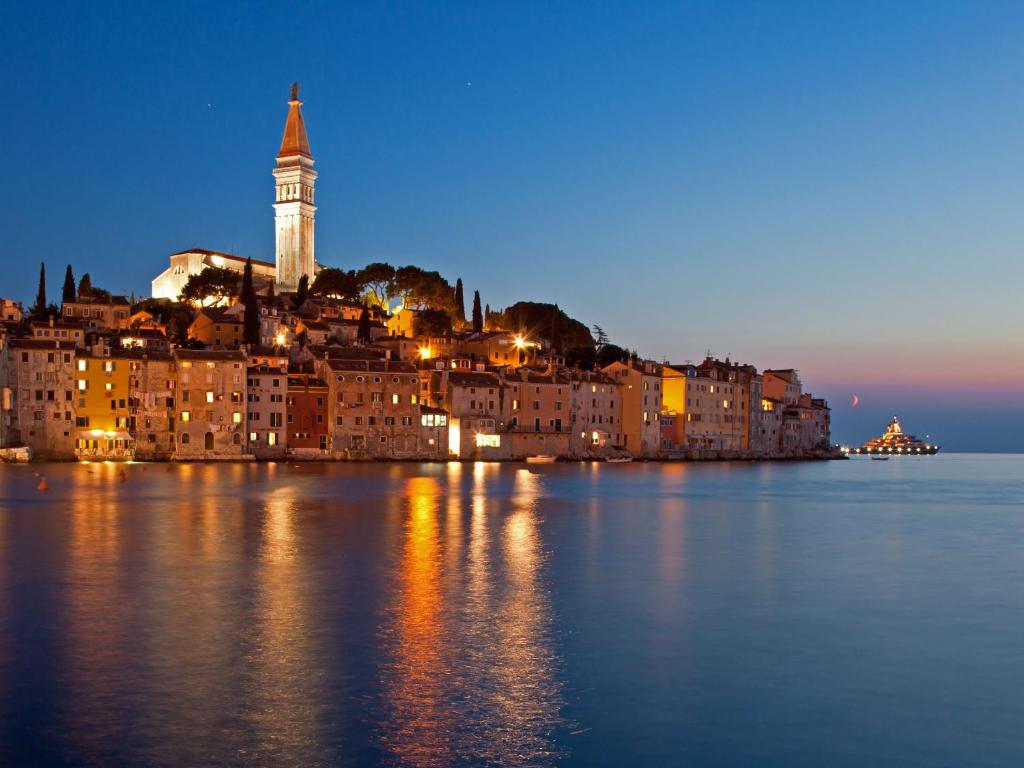 a city with a clock tower in the water at night at Apartments Cvek 2 in Rovinj