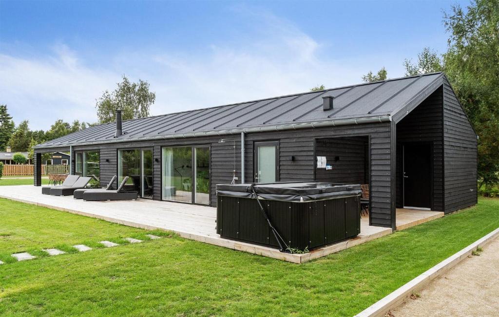 a black house with a hot tub in the yard at Amazing Home In Væggerløse With Sauna in Marielyst
