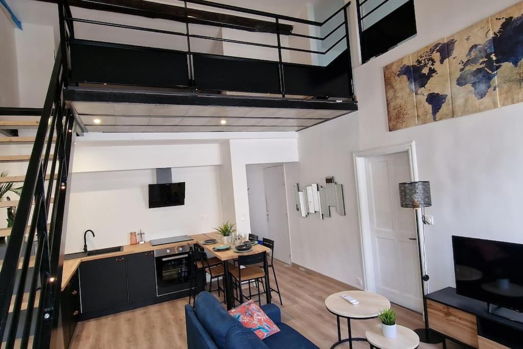 un salon avec un canapé bleu et une cuisine dans l'établissement Le loft du théâtre, à Montélimar