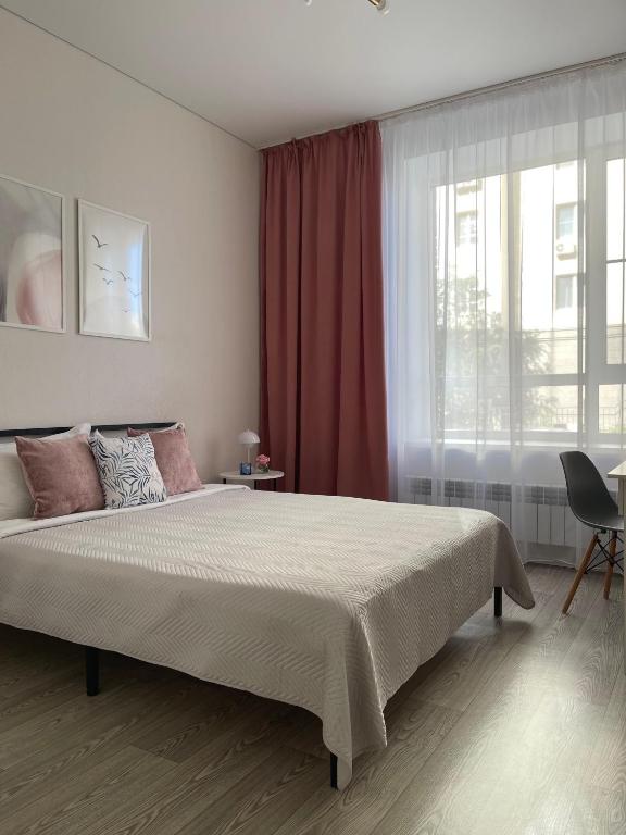 a bedroom with a large bed and a window at Alma Park in Taldykolʼ