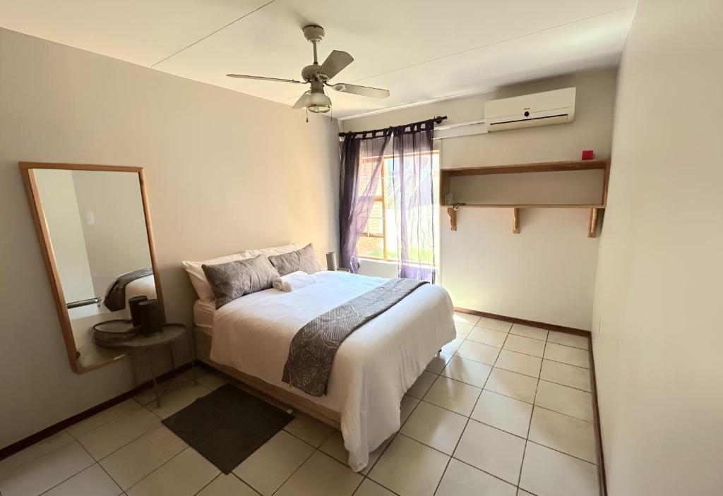 a bedroom with a bed and a mirror and a window at Cozy secure apartment in Bloemfontein