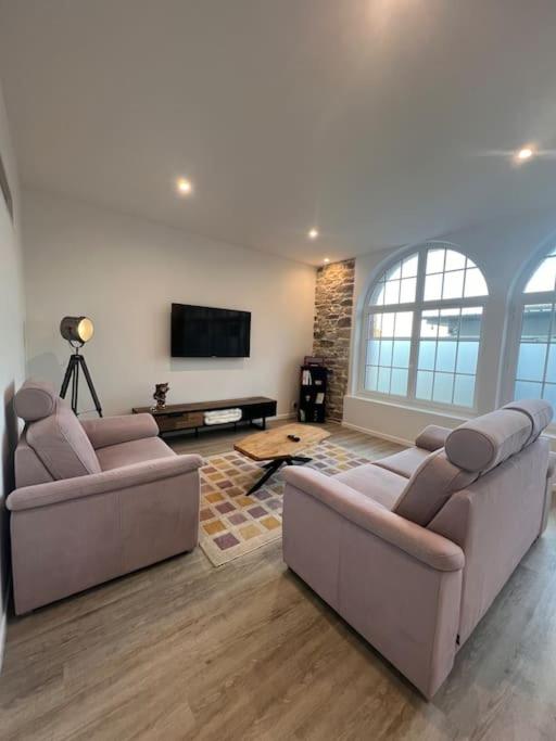 un salon avec deux canapés et une télévision à écran plat dans l'établissement Séjour au bord de la mer, à Barneville-Carteret