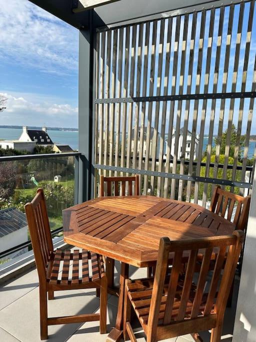 une table en bois et deux chaises sur un balcon dans l'établissement Appartement vue mer, plage et centre ville à pied, à Concarneau