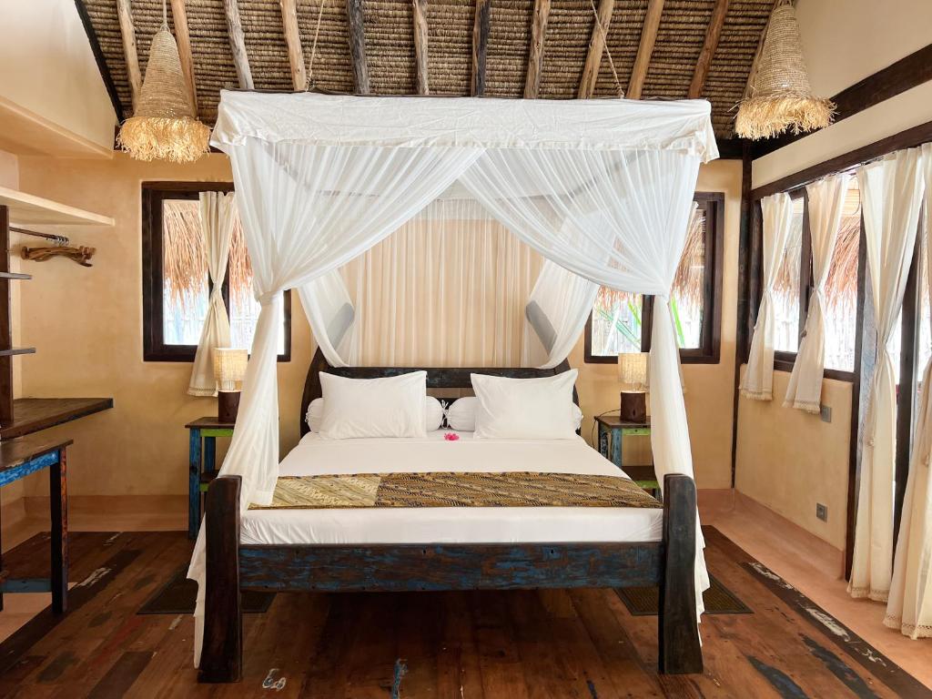 a bedroom with a bed with a canopy at Gili Asahan Eco Lodge & Restaurant in Gili Asahan