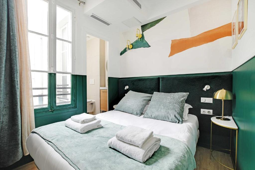 - une chambre verte et blanche avec un lit et des serviettes dans l'établissement Modern Studio with A-C - Near Montmartre, à Paris