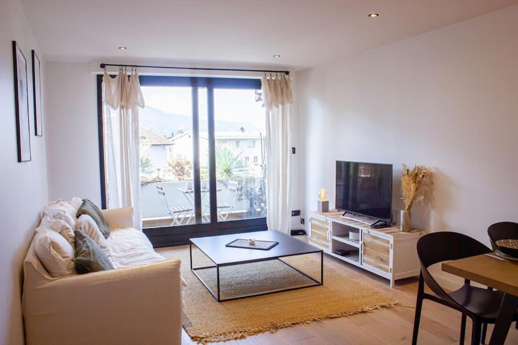 Una sala de estar con un sofá, una mesa y un televisor. en Le coquillage - Balcon & parking, en Albertville
