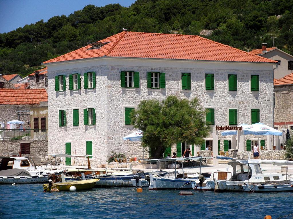 un grand bâtiment avec des bateaux amarrés dans un port dans l'établissement Hotel Maestral, à Prvić Luka