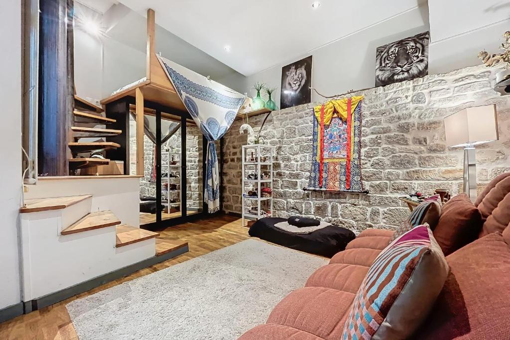 un salon avec un canapé et un mur en pierre dans l'établissement Charming Studio Near Le Louvre Rivoli, à Paris