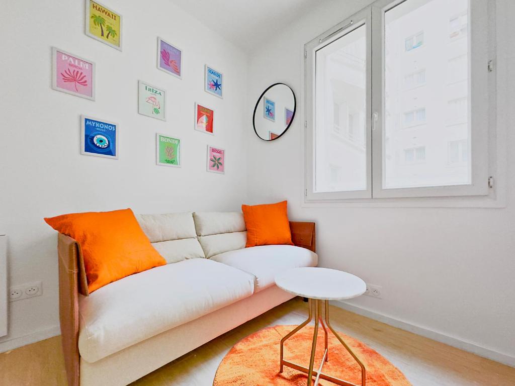 - un salon avec un canapé blanc et des oreillers orange dans l'établissement Charmant studio 2P - 5' Tour Eiffel, à Paris