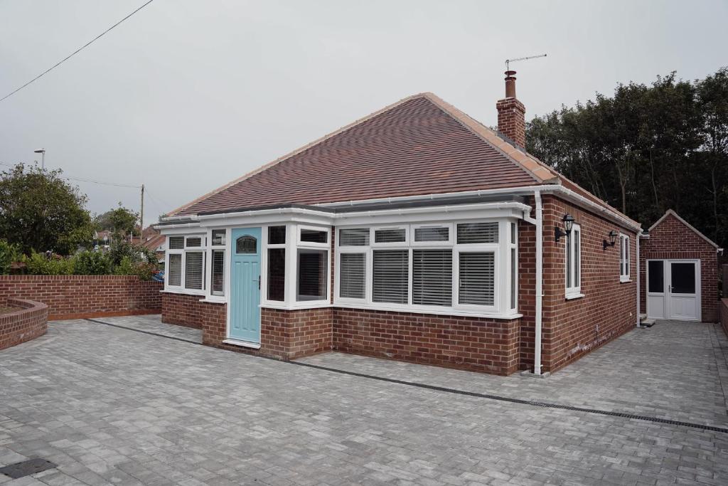 ein Backsteinhaus mit einer blauen Tür auf einer Einfahrt in der Unterkunft Lime Kiln Cottage in Bridlington