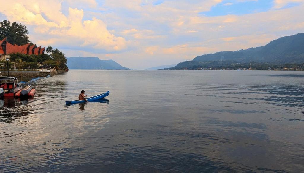 a person in a kayak on a large body of water at Zoé’s Paradise Waterfront Hotel in Tuktuk Siadong