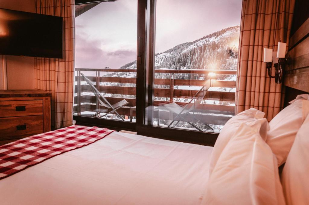 a bedroom with a bed and a large window at Hôtel Alpen Ruitor in Méribel