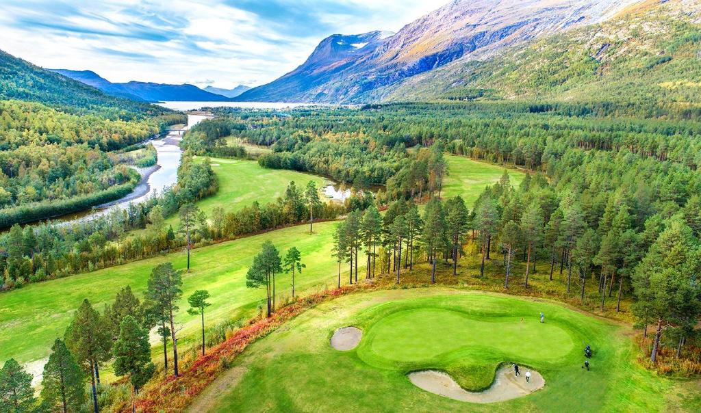 an aerial view of a golf course with a river and mountains at Skjomen kro og motell in Elvegård