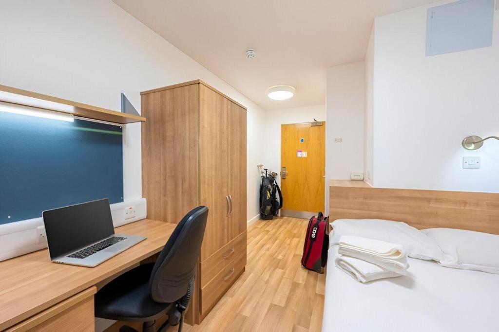 a bedroom with a desk with a laptop on a bed at UHI Dornoch- Campus Accommodation in Dornoch