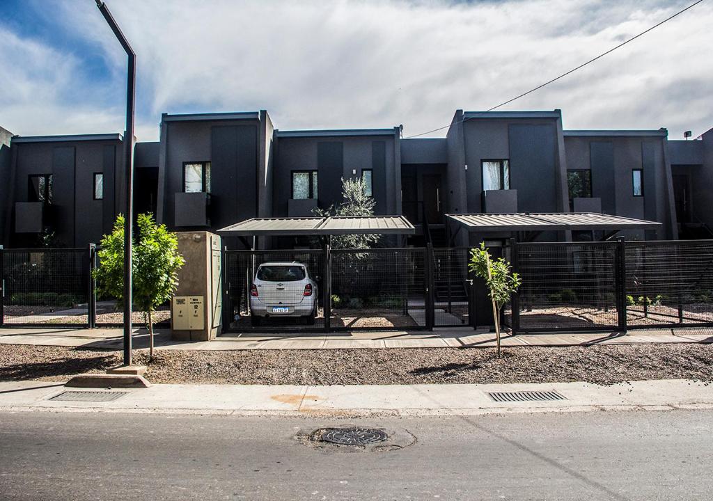 a van parked in front of a black building at Depto del Bosque, 4 personas, patio, cochera cubierta ,parrilla in Maipú