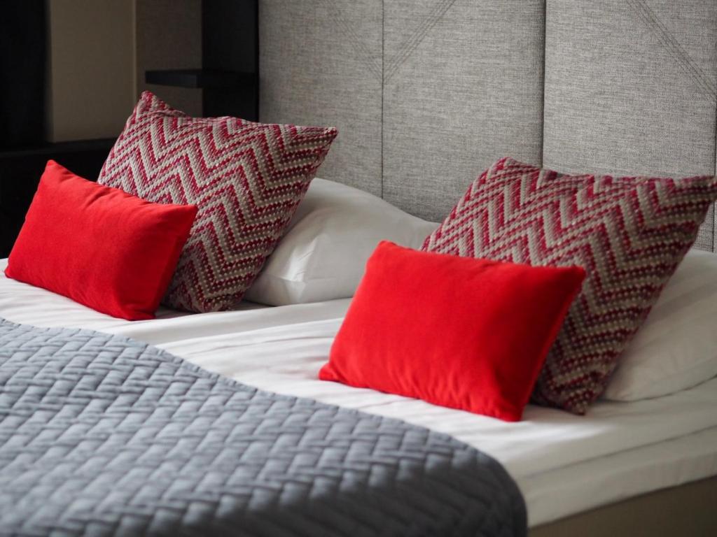 a bed with four red pillows on it at Santa's Hotel Santa Claus in Rovaniemi