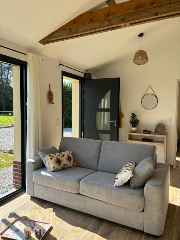 - un salon avec un canapé gris et des portes coulissantes en verre dans l'établissement Maison entre campagne et mer, à Sainte-Marguerite