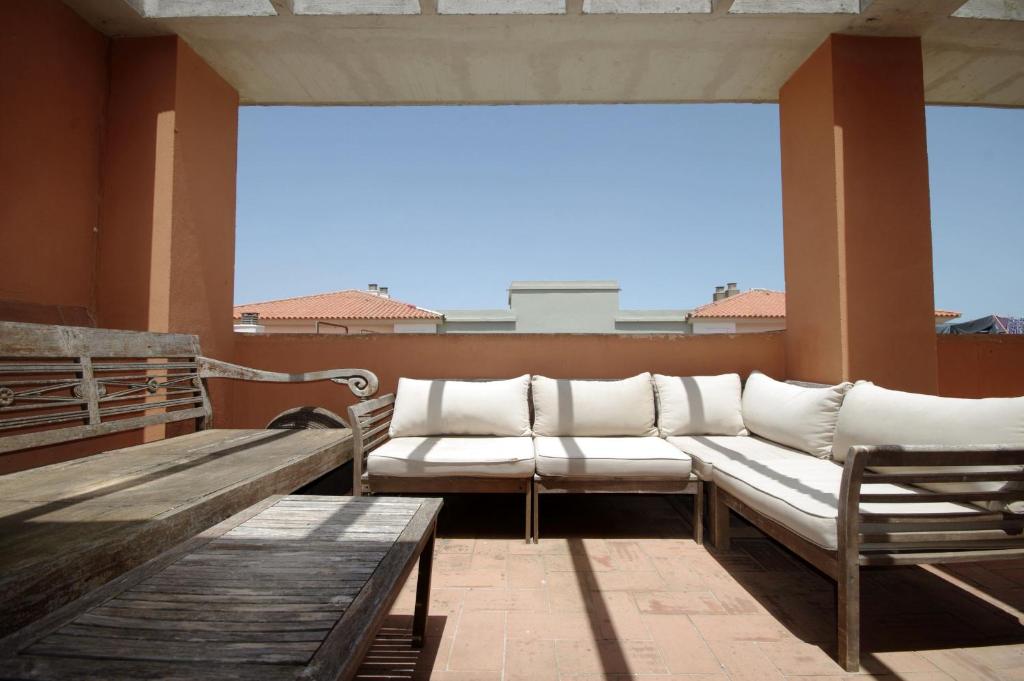 a porch with a couch and benches on a balcony at Apartamento Livingtarifa Canela in Tarifa