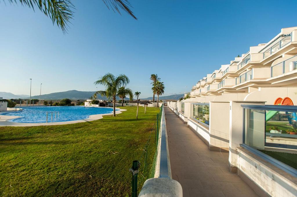 balkon budynku z basenem i palmami w obiekcie Livingtarifa Apartamento La Marea w mieście Tarifa