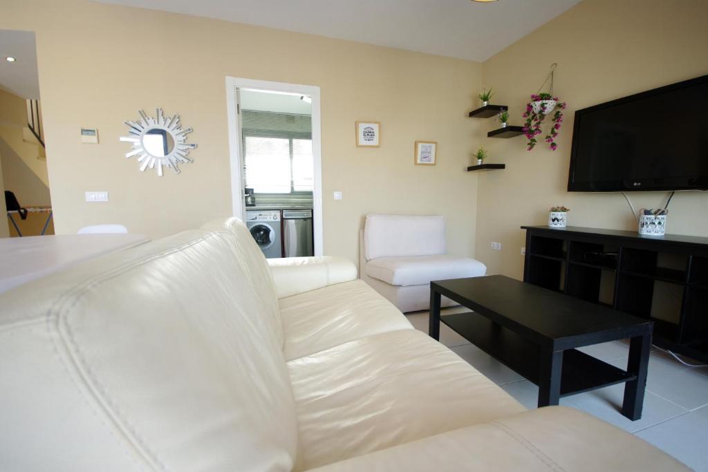 a living room with a white couch and a tv at Livingtarifa Apartamento Entre Dos Aguas in Tarifa