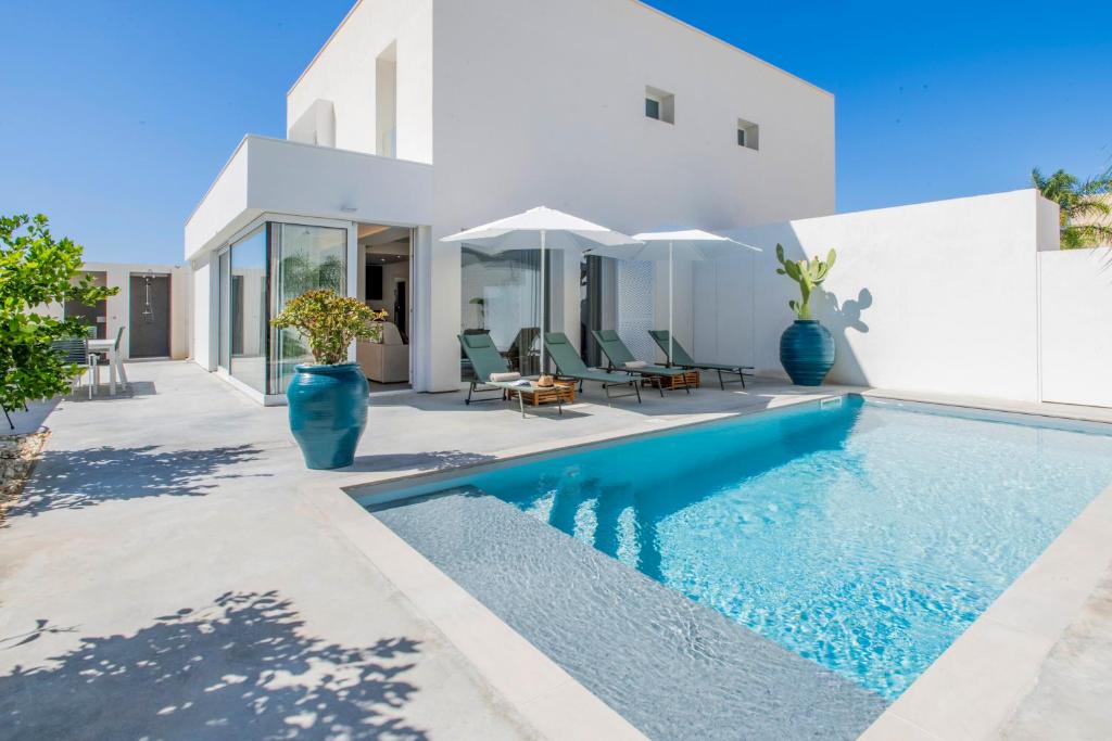 a swimming pool in front of a white house at SIMANA Mediterranean Pool Villas in Marina di Ragusa