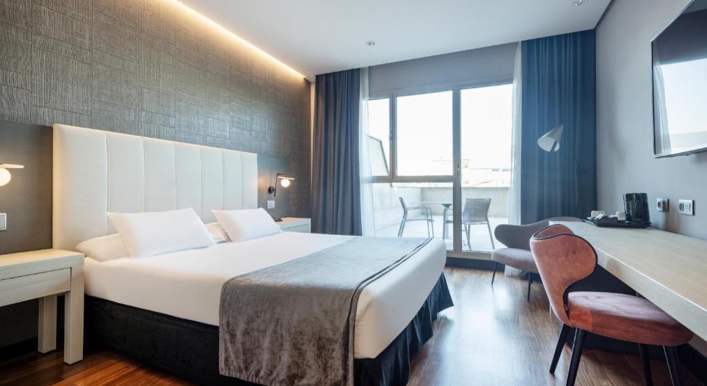 een hotelkamer met een groot bed en een tafel bij Ilunion Alcalá Norte in Madrid