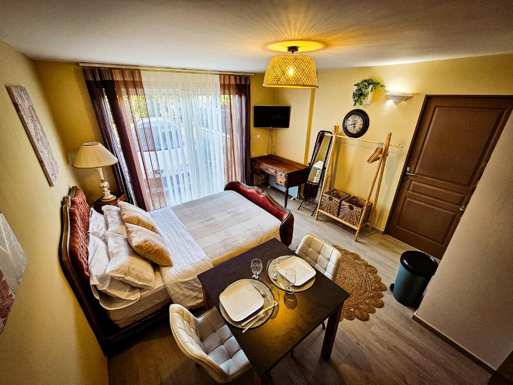 a bedroom with a large bed and a table with chairs at Appart type Hôtel, à 4 min du centre ville de Vaison-la-Romaine in Vaison-la-Romaine