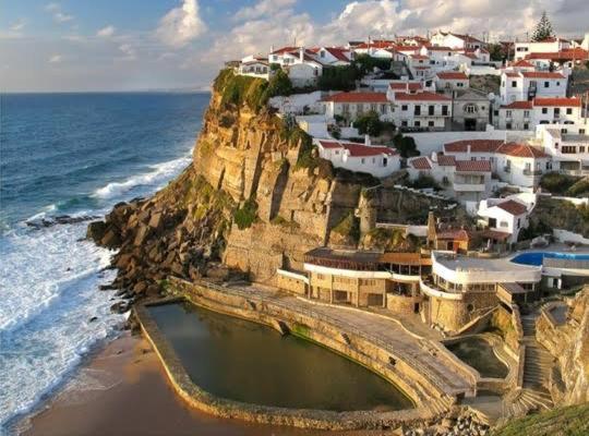 a town on top of a cliff next to the ocean at CasAzulApartments in Sintra