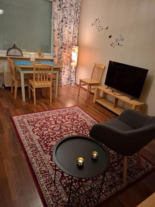 a living room with a table and a rug at Tunnelmallinen retroyksiö in Rovaniemi