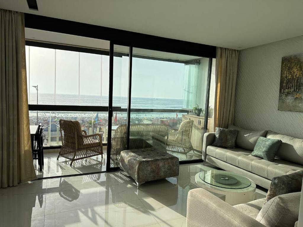 La perle de Mehdia sea view appartement في Mehdiya-Plage: غرفة معيشة مع أريكة ونافذة كبيرة