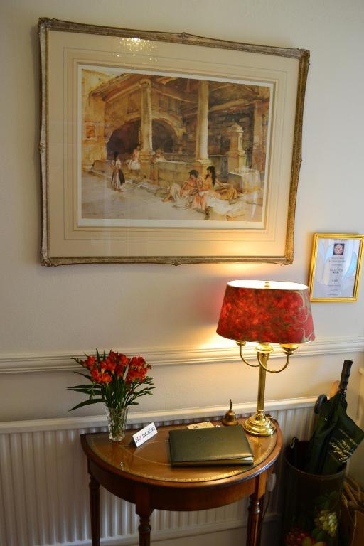 a table with a lamp and a picture on the wall at Knightsrest in Burnham on Sea