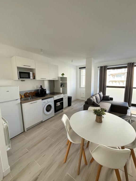 une cuisine et un salon avec une table et des chaises blanches dans l'établissement Appartement Hyper-centre ville, à Caen