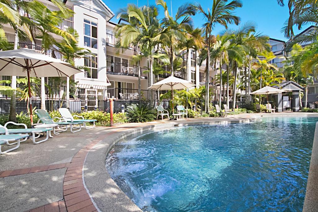 a swimming pool with chairs and umbrellas next to a building at Blue Waters Apartments in Gold Coast