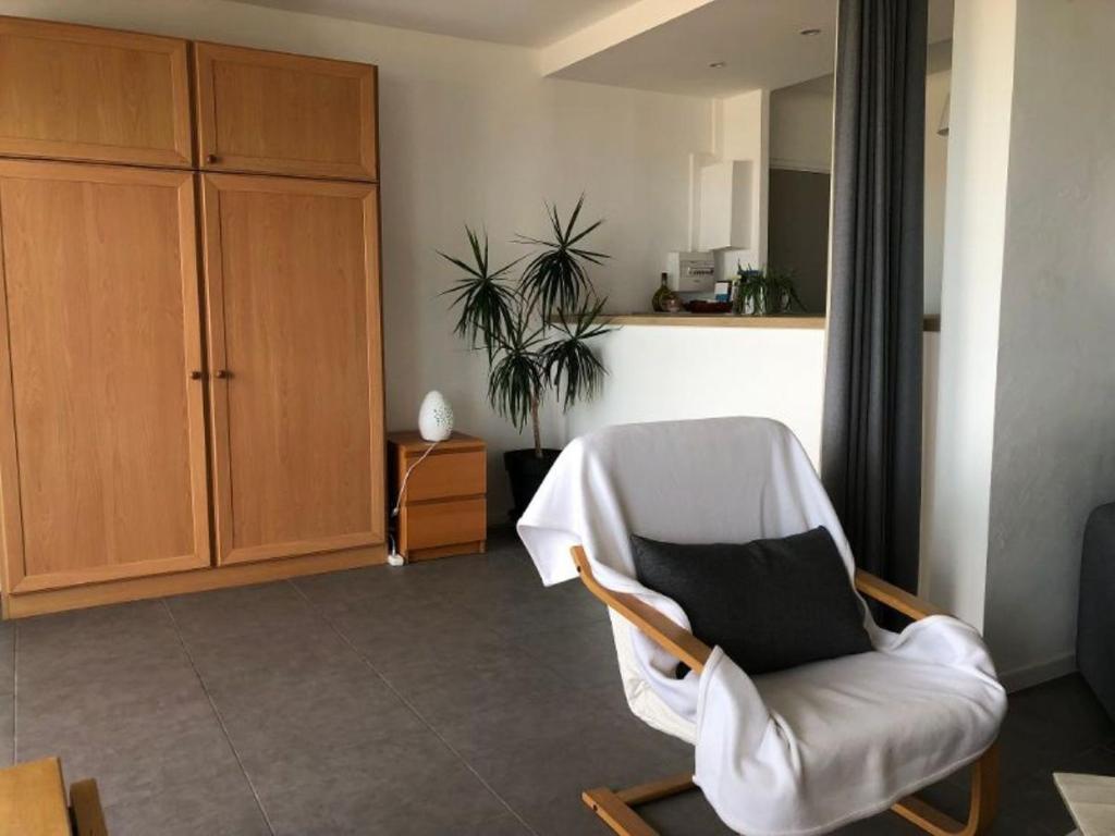 ein Wohnzimmer mit einem weißen Stuhl und einem schwarzen Kissen in der Unterkunft Anglet sables d'or - vue océan in Anglet