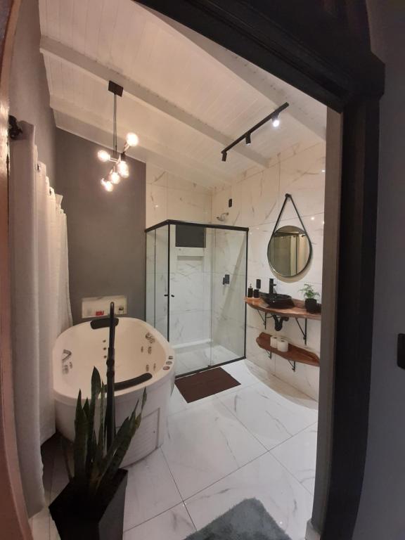 a bathroom with a tub and a shower and a sink at Cabana Lago Campestre in Urubici