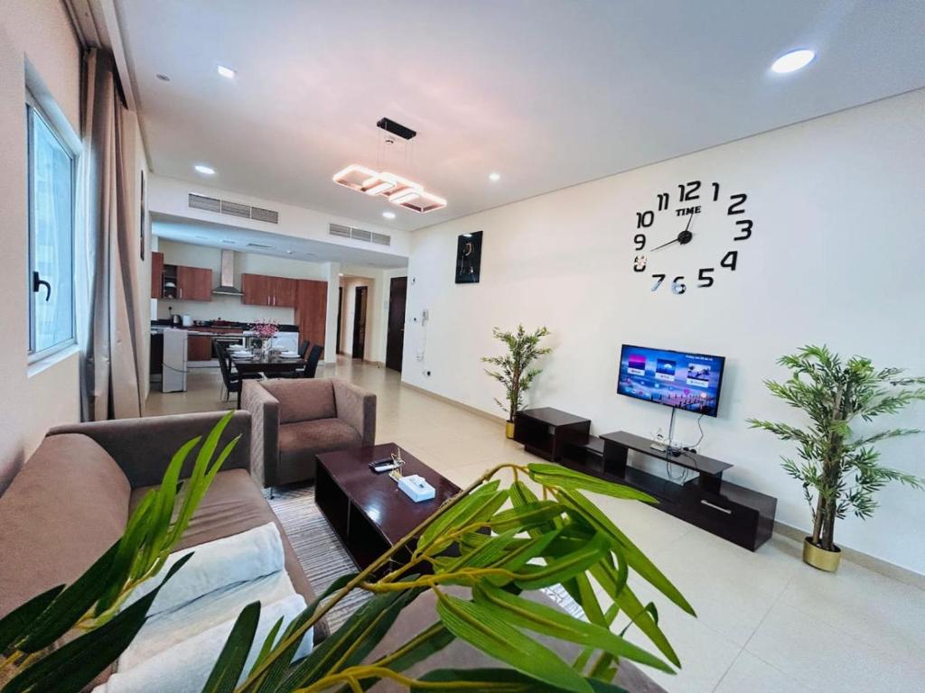 a living room with a couch and a clock on the wall at Aspire Tower-Two Bedroom Palm Stay in Manama