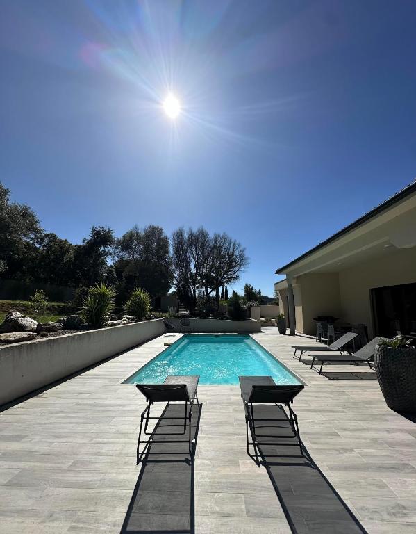 une piscine avec des chaises longues à côté d'un bâtiment dans l'établissement VILLA BENOA, à Oletta