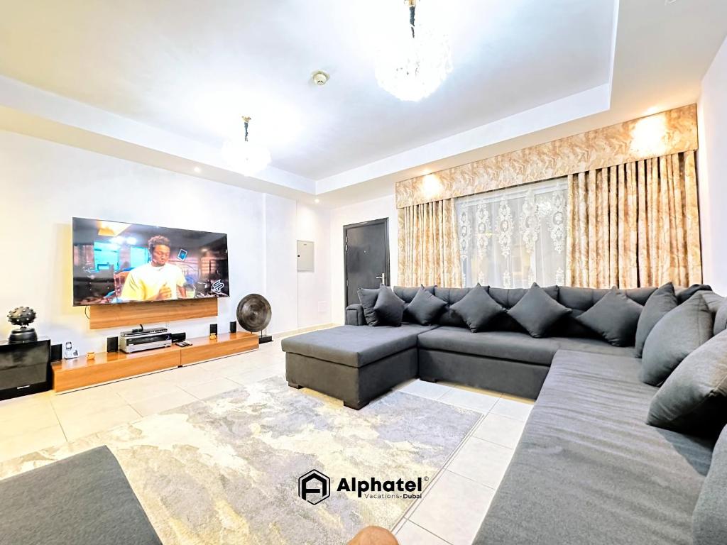 ein Wohnzimmer mit Couch und Flachbildfernseher in der Unterkunft Stylish 3-bedroom plus Maid room - Villa in JVC - Dubai in Dubai
