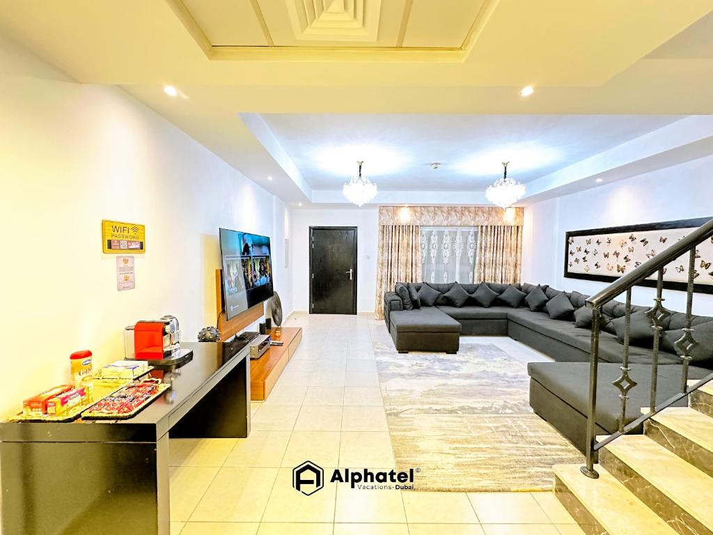 ein Wohnzimmer mit Couch und Fernseher in der Unterkunft Stylish 3-bedroom plus Maid room - Villa in JVC - Dubai in Dubai