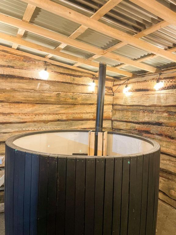 a room with a wooden wall with a tub in it at Cabaña termas de chillan, con tinaja in Recinto