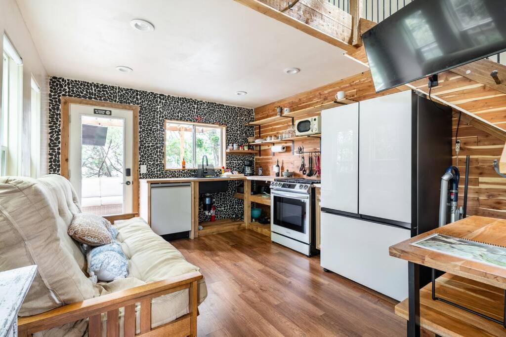 a living room with a couch and a kitchen at Cozy Coop Casita - Lake Travis-Hot Tub-Tiny House in Austin